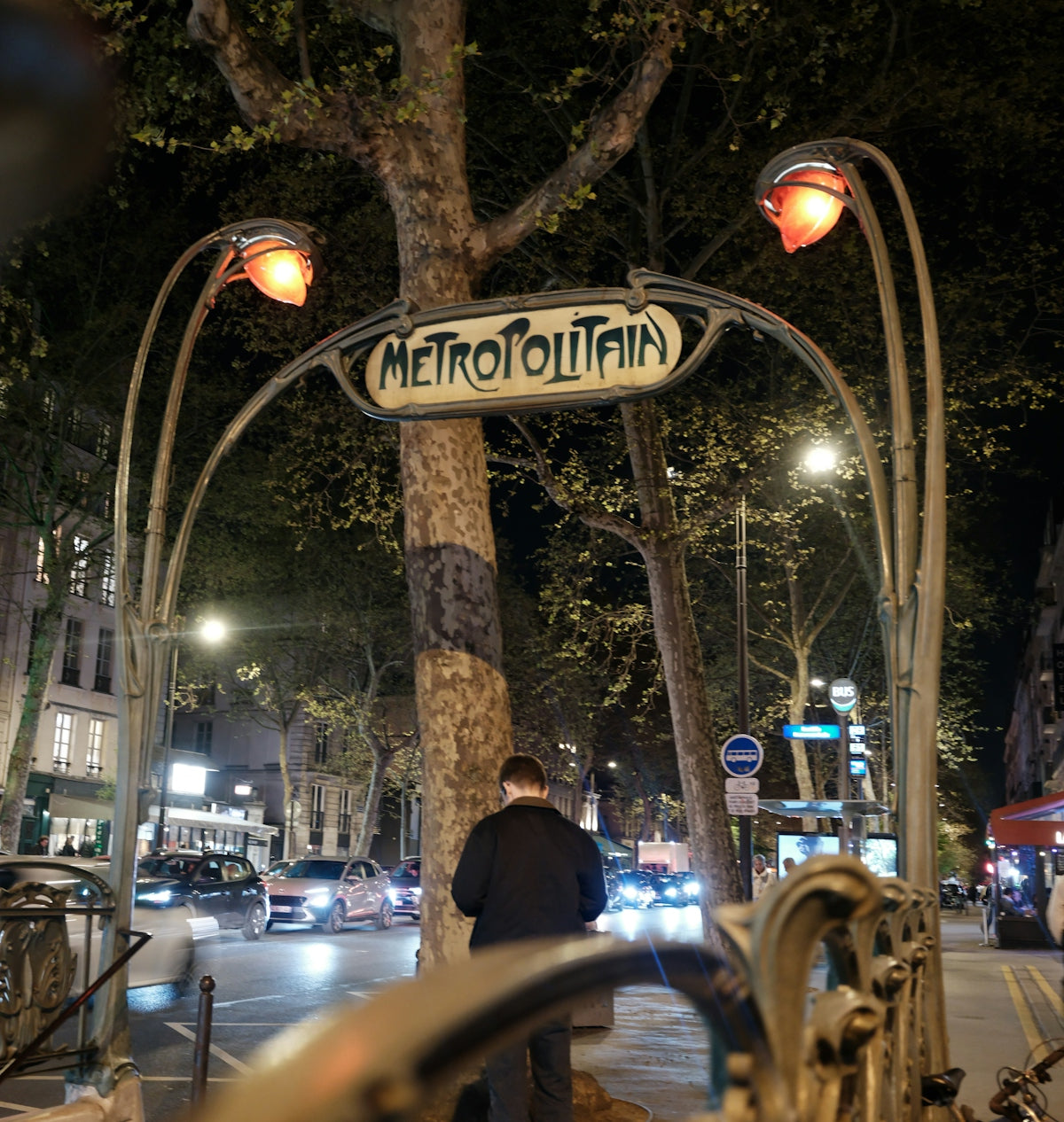 Parisian metro entrance at night with a person